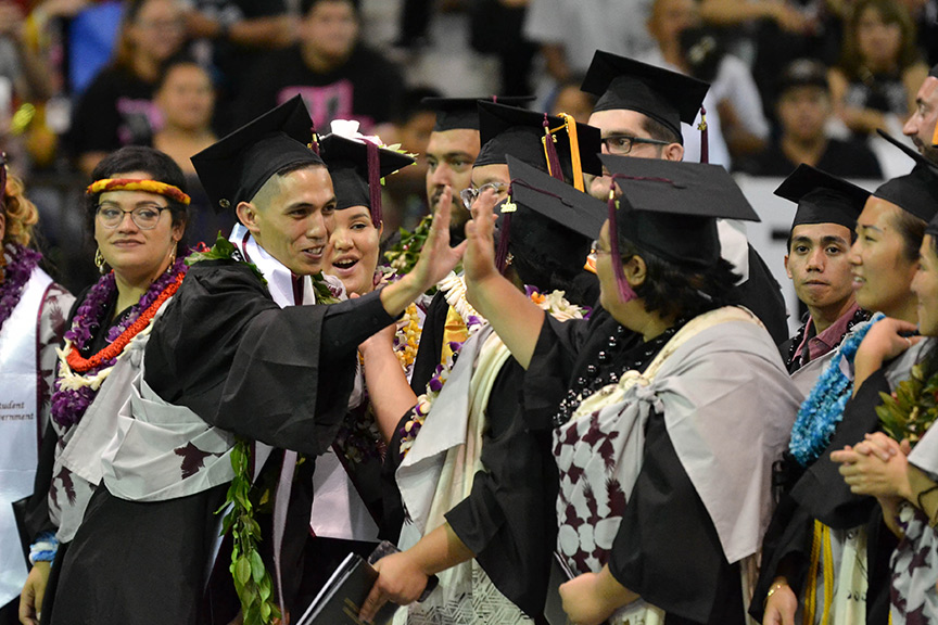 Student hi-fiving at commencement