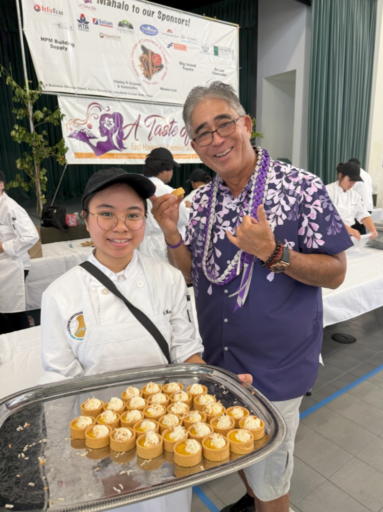  Hawai'i CC Culinary Program student Keala Banashian offers event emcee Dwayne Mukai a liliko'i tart.