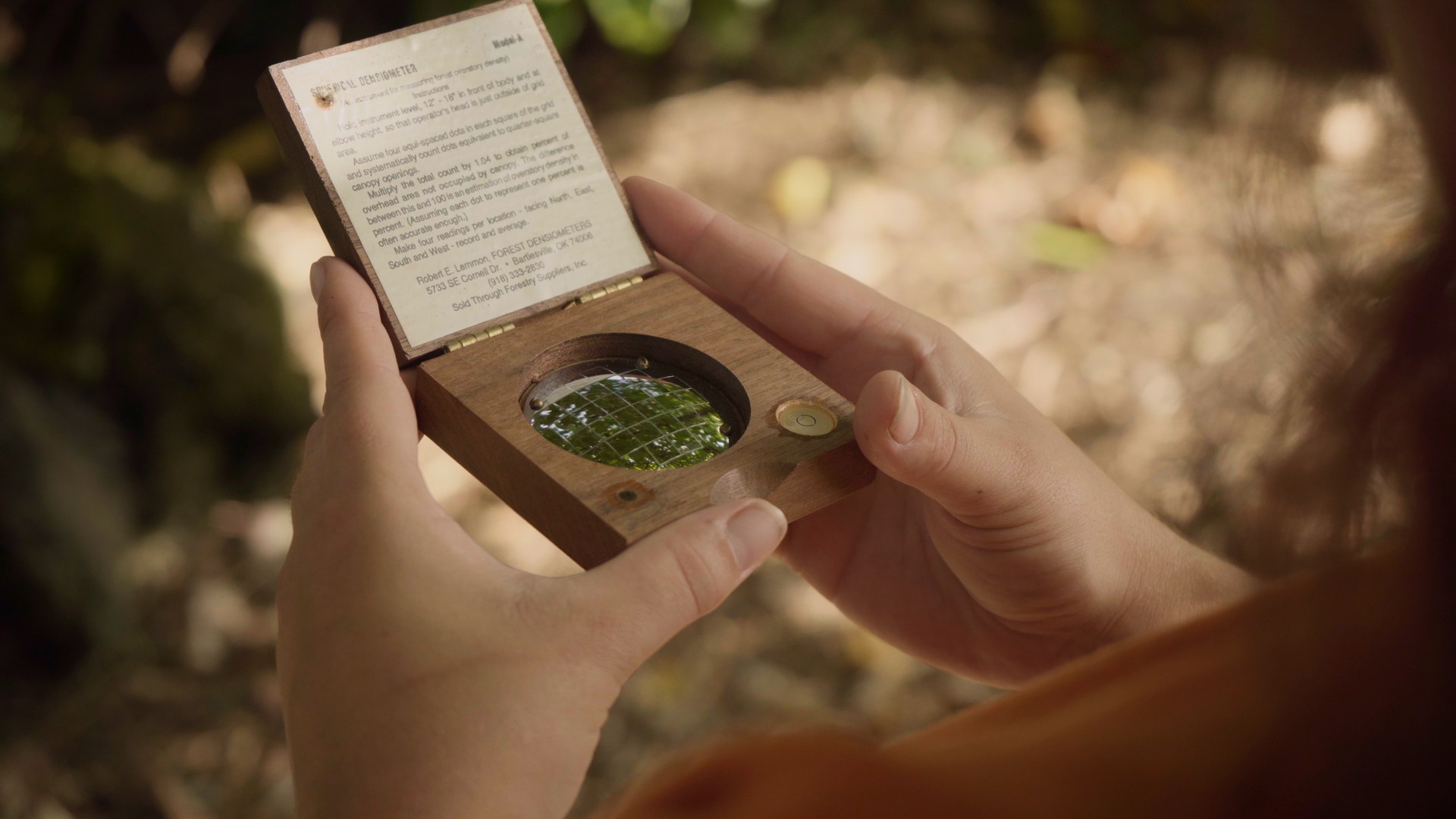 A TEAM student uses a densiometer (a handheld convex mirror) to measure the canopy cover. Traditional skills such as compass navigation and plant identification, along with the integration of Hawaiian cultural knowledge into forest management, are important skills taught in the TEAM program.